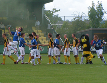 Brønshøj, Holbæk og Hvepsen Verner løber på banen i tyk tåge af gul røg fra supporterklubben Hvepsenes DBU-godkendte festfyrværkeri (foto: T. Brygger)